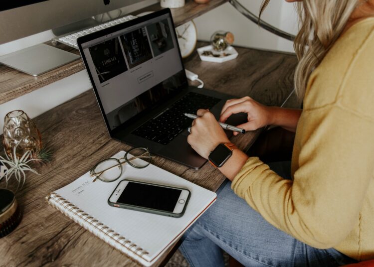 person in blue denim jeans using macbook pro